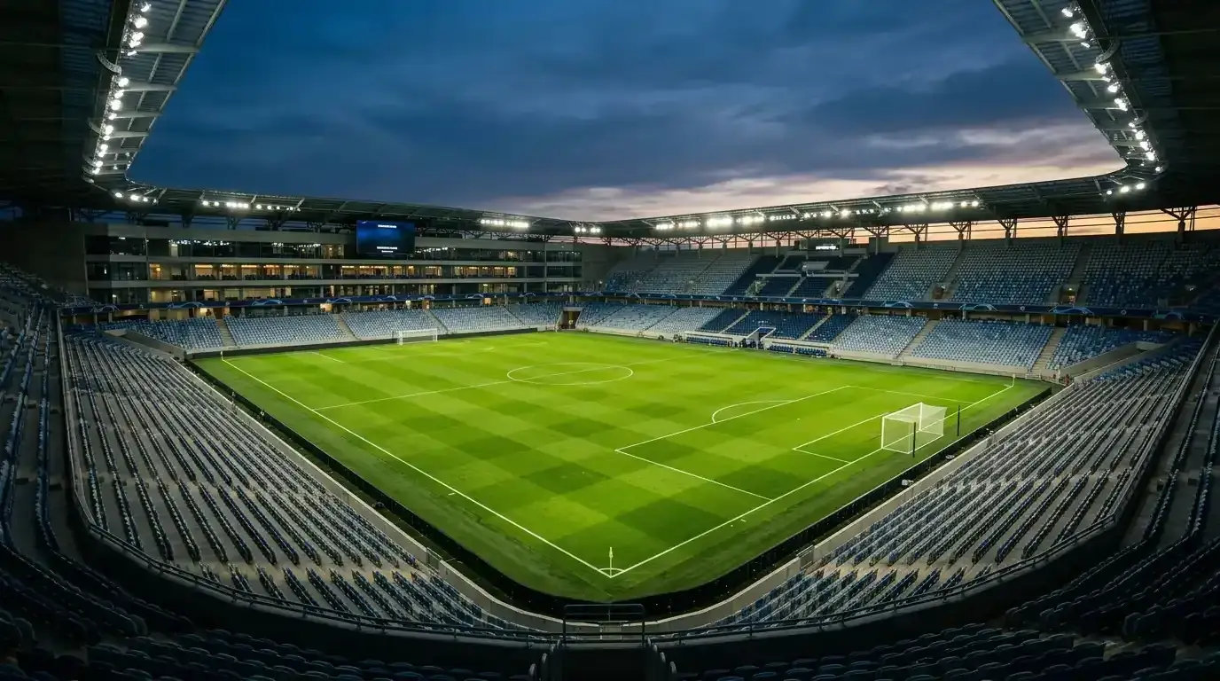 Nogometni travnjak i tribine osvijetljenog stadiona uoči večernje utakmice pod reflektorima.