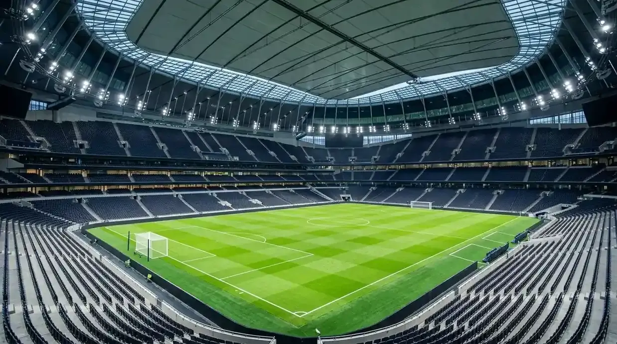 Nogometni travnjak modernog stadiona s zatvorenim krovom pod umjetnim svjetlom prije utakmice.